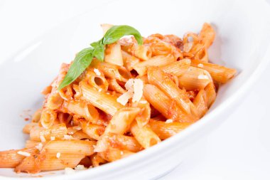 Peynirli makarna ve fesleğenle süslenmiş güneşte kurutulmuş domates.