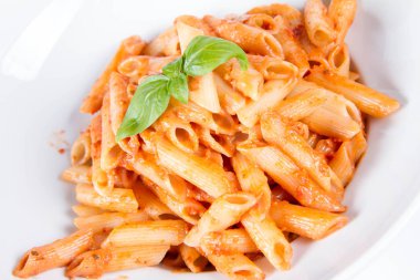 Peynirli makarna ve fesleğenle süslenmiş güneşte kurutulmuş domates.