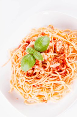 Beyaz arka planda fesleğenle süslenmiş erimiş parmesan peynirli spagetti bolonez.