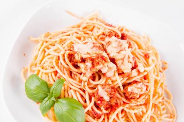 Beyaz arka planda fesleğenle süslenmiş erimiş parmesan peynirli spagetti bolonez.