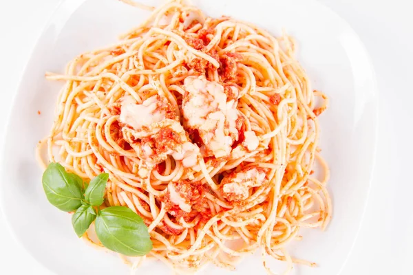 Beyaz arka planda fesleğenle süslenmiş erimiş parmesan peynirli spagetti bolonez.