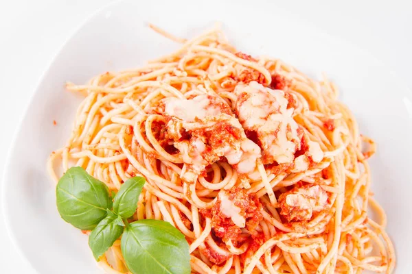 Beyaz arka planda fesleğenle süslenmiş erimiş parmesan peynirli spagetti bolonez.