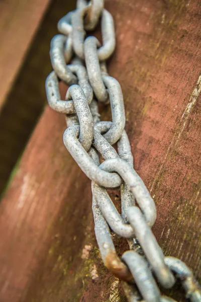 Metal link chain on a wooden gate in close up