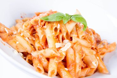 Peynirli makarna ve fesleğenle süslenmiş güneşte kurutulmuş domates. 