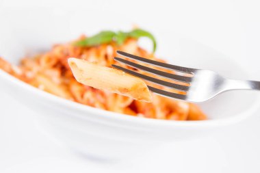 Pesto soslu makarna ve çatalla yenmiş fesleğenle süslenmiş kurutulmuş domates.