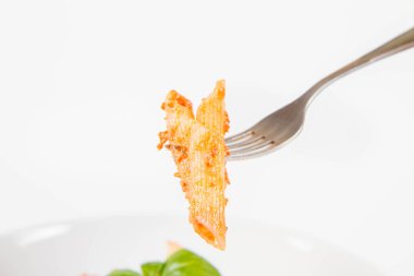 Pesto soslu makarna ve çatalla yenmiş fesleğenle süslenmiş kurutulmuş domates.