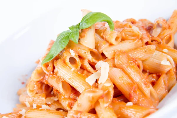 Peynirli makarna ve fesleğenle süslenmiş güneşte kurutulmuş domates. 