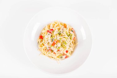 Krema soslu spagetti tütsülenmiş uskumru, bezelye, dolma biber ve beyaz bir tabakta maydanoz.