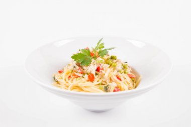 Krema soslu spagetti tütsülenmiş uskumru, bezelye, dolma biber ve beyaz bir tabakta maydanoz.