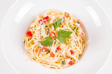 Krema soslu spagetti tütsülenmiş uskumru, bezelye, dolma biber ve beyaz bir tabakta maydanoz.