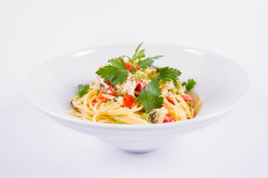 Krema soslu spagetti tütsülenmiş uskumru, bezelye, dolma biber ve beyaz bir tabakta maydanoz.