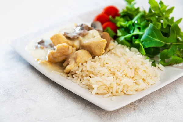 Pieces of chicken fillet cooked in a cream sauce with mushrooms and lemon juice, served with rice.