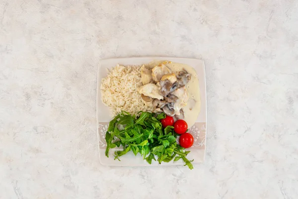 Pieces of chicken fillet cooked in a cream sauce with mushrooms and lemon juice, served with rice.