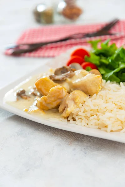 Pieces of chicken fillet cooked in a cream sauce with mushrooms and lemon juice, served with rice.