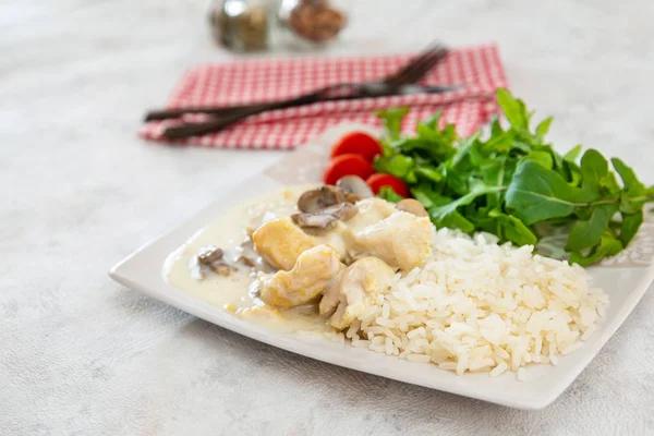 Pieces of chicken fillet cooked in a cream sauce with mushrooms and lemon juice, served with rice.