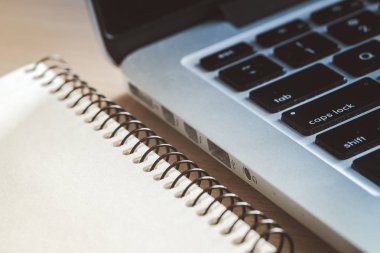 Ahşap ofis resepsiyon masası Not defteri açık ve bilgisayar ile. Yan görünümü. Parlak nokta sarı tonda. Mavi gölgeler tonda. Sınavlara hazırlık.