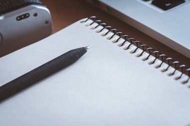 Ahşap ofis resepsiyon masası kamera defter, kalem ve bilgisayar ve retro. Yan görünümü. Parlak nokta mavi tonda. Sınavlara hazırlık. Düşük anahtar atış.