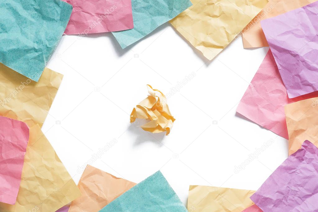 Background of many crumpled sticky orange, green, yellow, purple and pink reminder notes with shadows framed with one crumpled piece in center