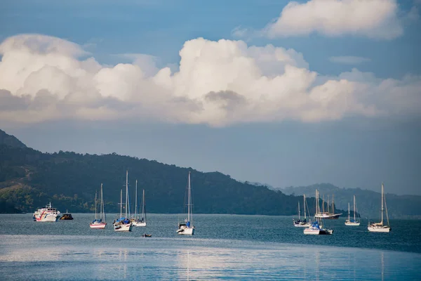 Многие Лодки Стоящие Якоре Голубых Водах Гавани Горами Облаками Заднем — стоковое фото