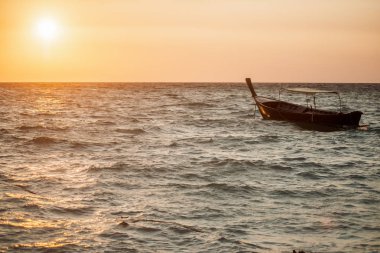Bir tekne gündoğumu sırasında okyanusta yüzen.