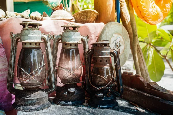 Three Lantern kerosene oil lamps on a sunny beach