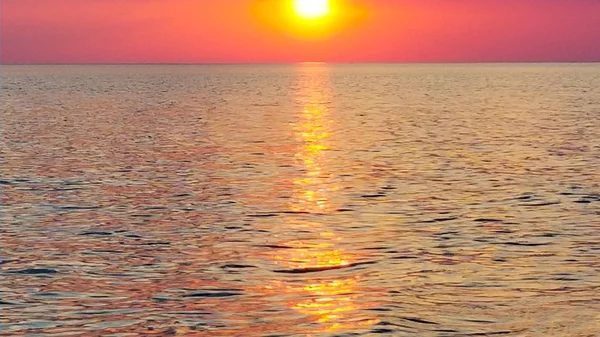 La puesta de sol naranja reflejada en las pequeñas olas. Las olas brillantes en la puesta del sol — Foto de Stock