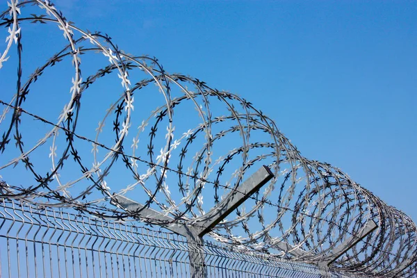 Fence with barbed wire against the blue sky. Symbol of freedom of imprisonment — Stock Photo, Image