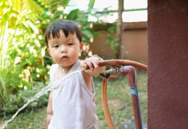 Kauçuk tüp oynayan ve ağaçları sulayan sevimli bebek çocuk