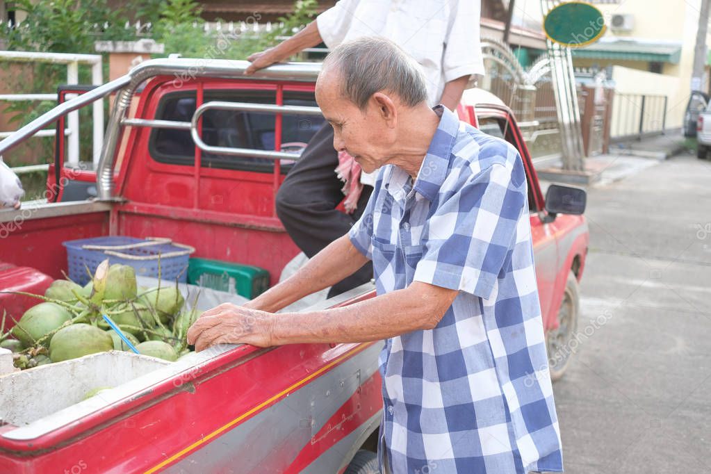 Old man choosing and buying coconuts on pickup truck