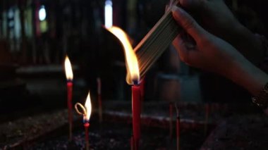 Kırmızı mumdan tütsü yakan kadın Buda 'ya, Çin tanrılarına dua etmek ve atalarımıza saygılarını sunmak için.