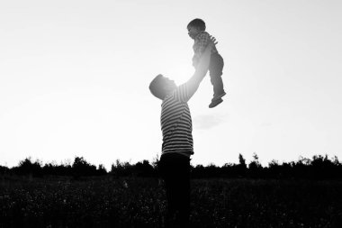 Gün batımında çiçek alandaki küçük oğluyla oynamaya baba