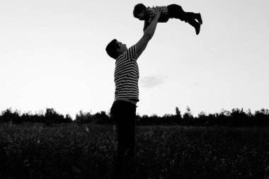 Gün batımında çiçek alandaki küçük oğluyla oynamaya baba