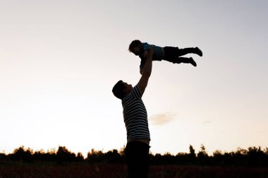 Baba ve oğul alanında günbatımı anda oynamak. İnsanlar sahada eğleniyor. Dostu aile ve yaz tatil kavramı
