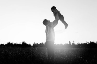 Gün batımında çiçek alandaki küçük oğluyla oynamaya baba