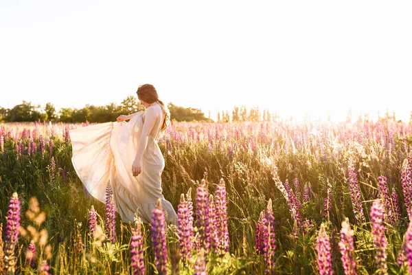 Giovane donna in piedi su un campo di fiori selvatici con alba sullo sfondo — Foto Stock