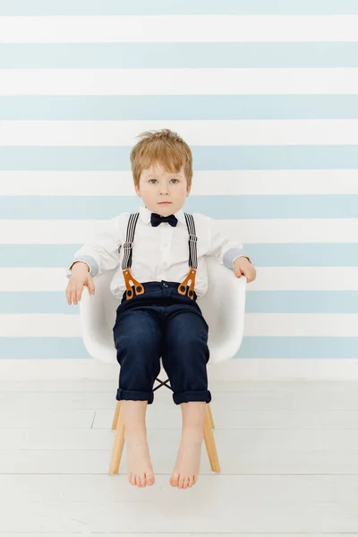 Caucasiano menino sentado em linha reta na cadeira — Fotografia de Stock