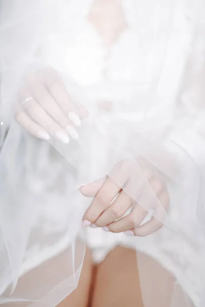 Руки невесты крупным планом на свадебное атласное платье — стоковое фото