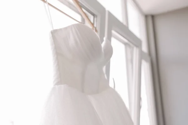 Vestido de casamento branco nos ombros perto da janela — Fotografia de Stock