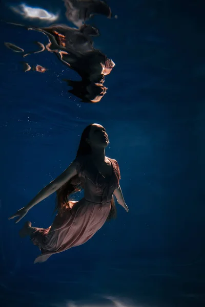 Активное время женщины, плавающей ночью под водой — стоковое фото