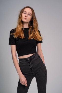 koyu giysiler içinde güzel zencefil kadın kamera bakarak ve gri stüdyo arka plan üzerinde poz