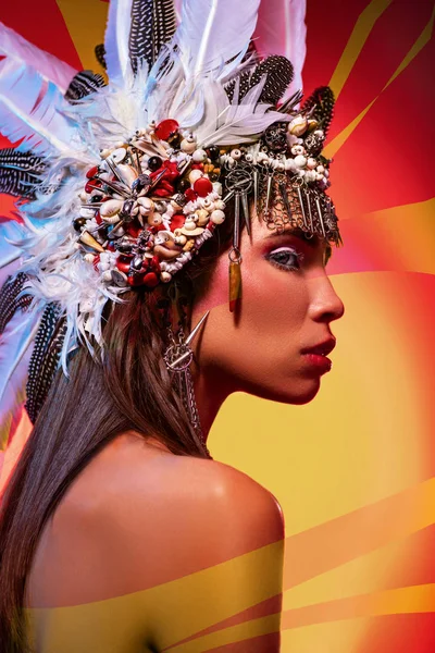 明るいオレンジ色の背景に部族の頭飾りの美しい裸の女性の側面図 — ストック写真