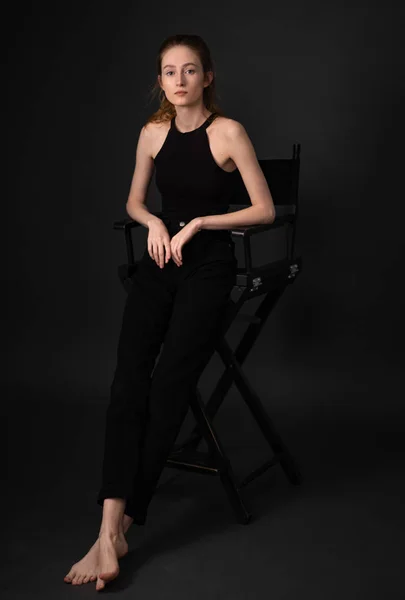 Όμορφη Μελαχρινή Μοντέλο Μαύρα Ρούχα Κάθεται Στην Καρέκλα Ενώ Ποζάρει — Φωτογραφία Αρχείου