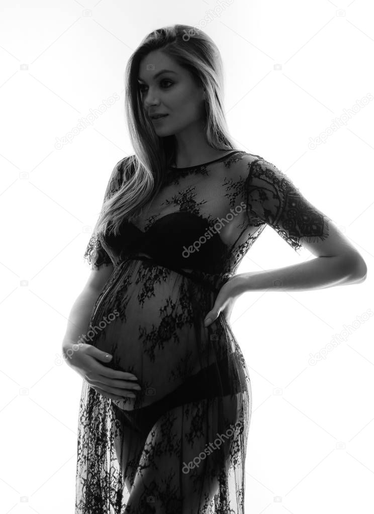 attractive pregnant woman in transparent lace dress posing isolated on white background