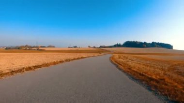 Sonbahar manzarasında araba sürüyor. Sonbahar ağaçları ve güneşli bir günde mavi gökyüzü. Kırsal yol. Sonbahar kavramı