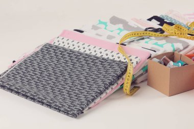 Terzi ya da ev ödevi için% 100 pamuk kumaş yığını, sarı terzi sayacı, iplik ve makas ile dikiş konsepti