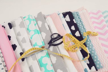 Terzi ya da ev ödevi için% 100 pamuk kumaş yığını, sarı terzi sayacı, iplik ve makas ile dikiş konsepti