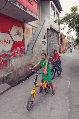 Manado, Endonezya - 03 Ağustos 2015: Gülümseyen ve kaygısız çocuk scooter gecekondu Manado şehrin Kuzey Sulawesi Adasında zavallı sokak ile.