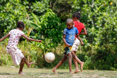 Maroantsetra, Madagaskar - 23 Kasım 2016: Mutlu Madagaskarlı çocuk, erkek ve kız çıplak ayak ile Madagaskar'daki Masoala yağmur ormanı yakınlarında onun köy arkasında futbol oynamak.