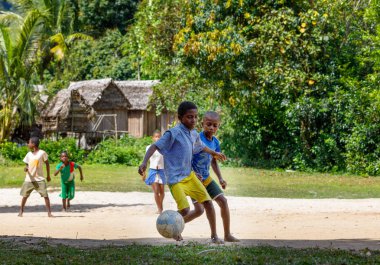 Maroantsetra, Madagaskar - 23 Kasım 2016: Mutlu Madagaskarlı çocuk, erkek ve kız çıplak ayak ile Madagaskar'daki Masoala yağmur ormanı yakınlarında onun köy arkasında futbol oynamak.