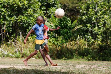 Maroantsetra, Madagaskar - 23 Kasım 2016: Mutlu Madagaskarlı çocuk, erkek ve kız çıplak ayak ile Madagaskar'daki Masoala yağmur ormanı yakınlarında onun köy arkasında futbol oynamak.
